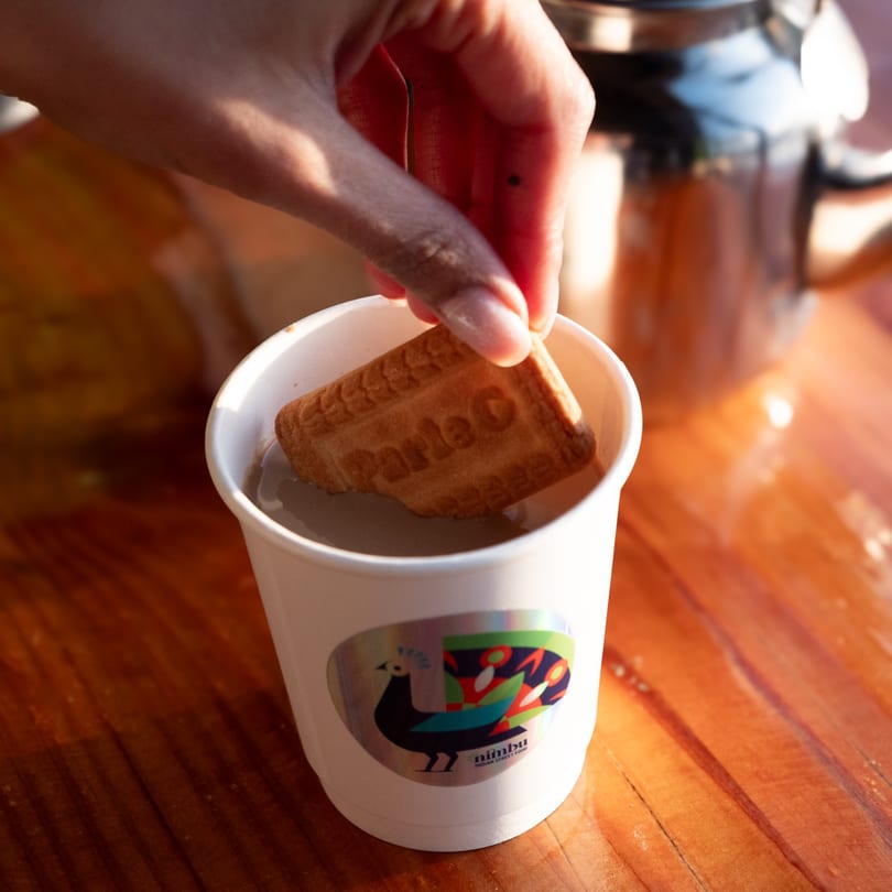 Hand dipping a Parle-G biscuit into a Nimbu branded cup of Indian chai.